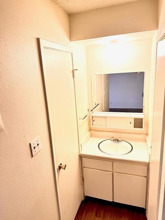 Bathroom with dark wood finished floors, vanity, and a textured ceiling