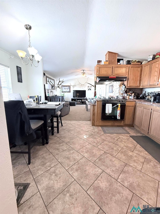 Kitchen featuring brown cabinets, lofted ceiling, open floor plan, black gas range, and pendant lighting