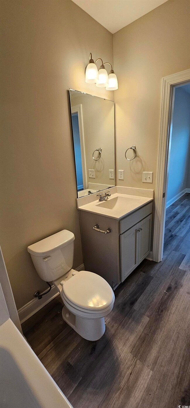 Half bathroom with wood finished floors and vanity
