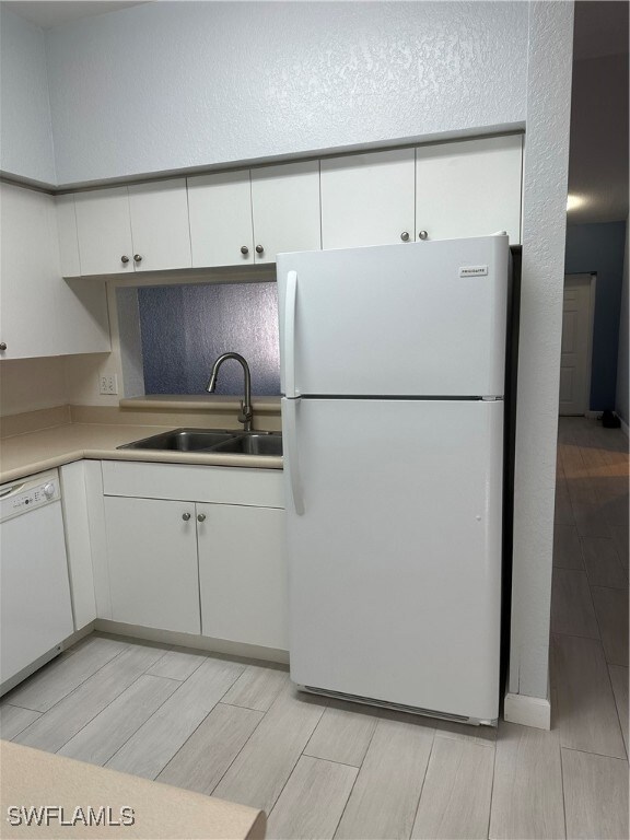 Kitchen featuring sink, white cabinetry, dishwashing machine, and white refrigerator