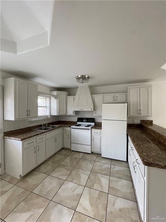 Kitchen featuring white appliances, premium range hood, white cabinets, and dark stone countertops