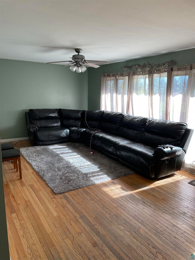 Living room with ceiling fan and hardwood / wood-s