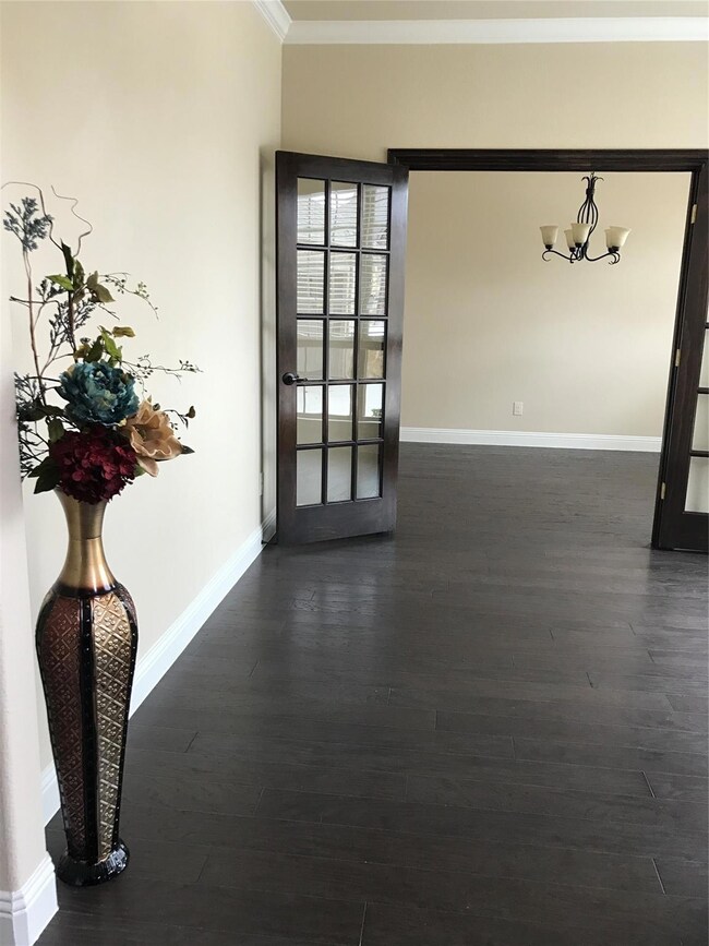 Spare room with dark hardwood / wood-style flooring, an inviting chandelier, crown molding, and french doors
