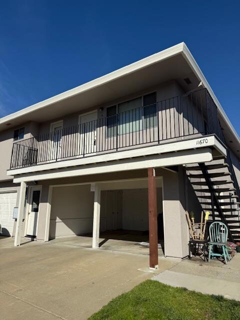 rear view of house featuring a balcony, driveway, and a garage