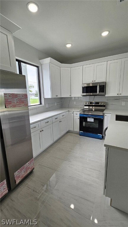 Kitchen featuring white cabinetry, appliances with