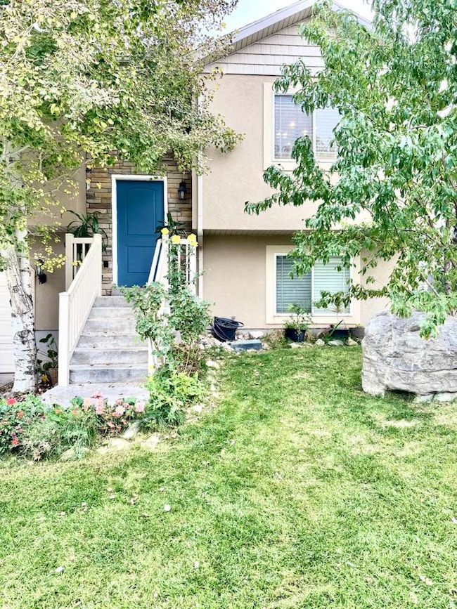 Rear view of property with stucco siding and a lawn