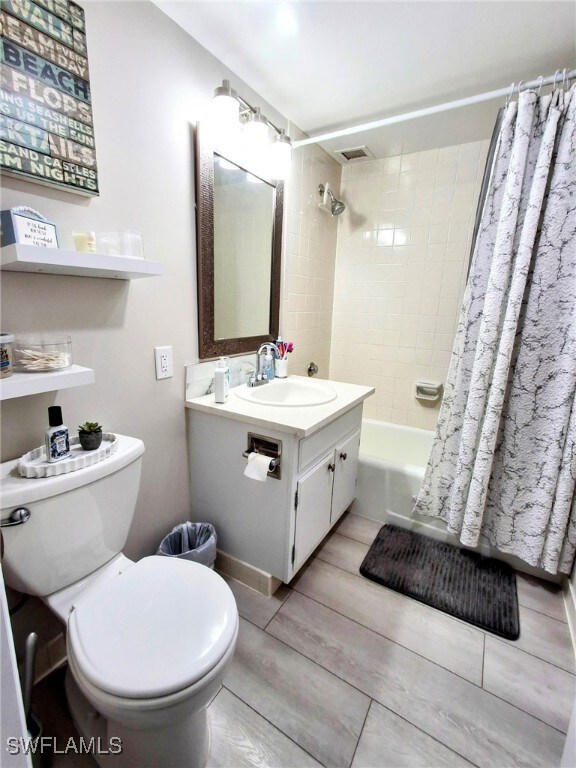 Full bathroom with vanity, shower / bath combo, and wood finished floors