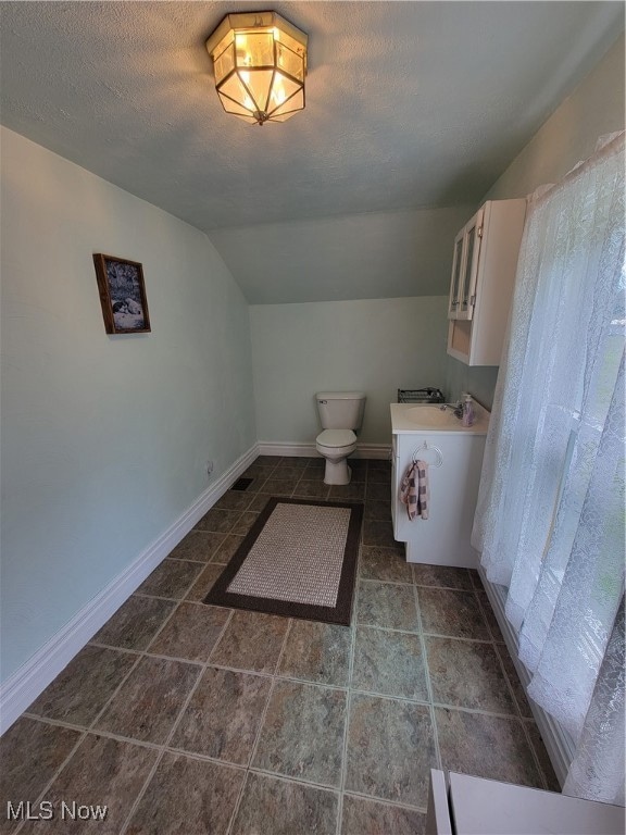 Bathroom with vaulted ceiling, vanity, and a textured ceiling