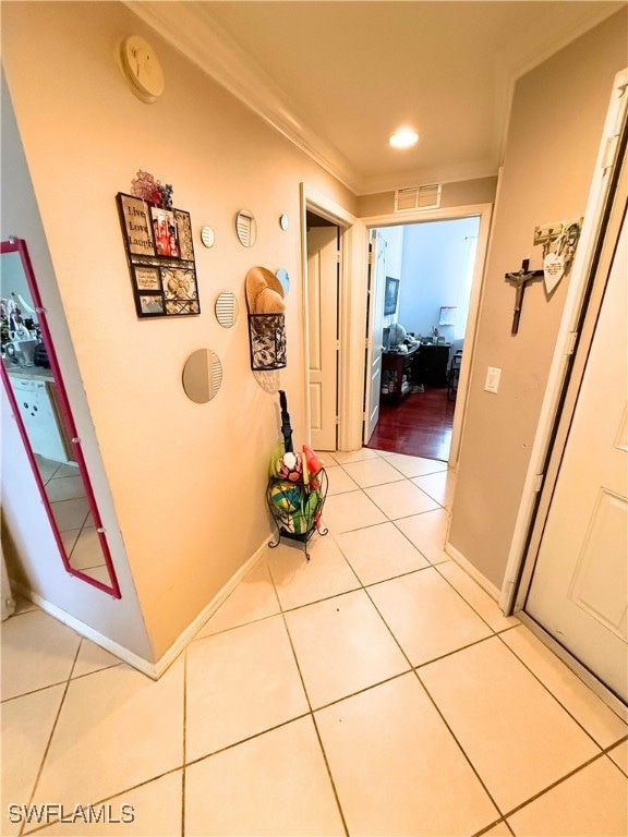 Corridor featuring light tile patterned floors and crown molding