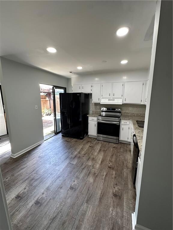 Kitchen featuring freestanding refrigerator, stove, exhaust hood, decorative backsplash, and dark wood-style flooring