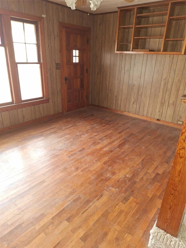 Empty room featuring wooden walls and light hardwo