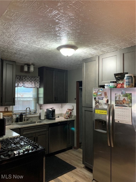 Kitchen with refrigerator, range, light wood-type flooring, dishwashing machine, and light stone countertops