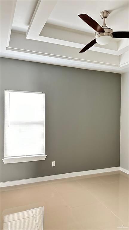 Tiled spare room with a ceiling fan and baseboards