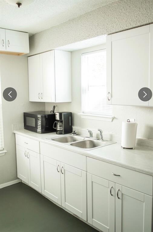 Kitchen featuring white cabinets, black microwave