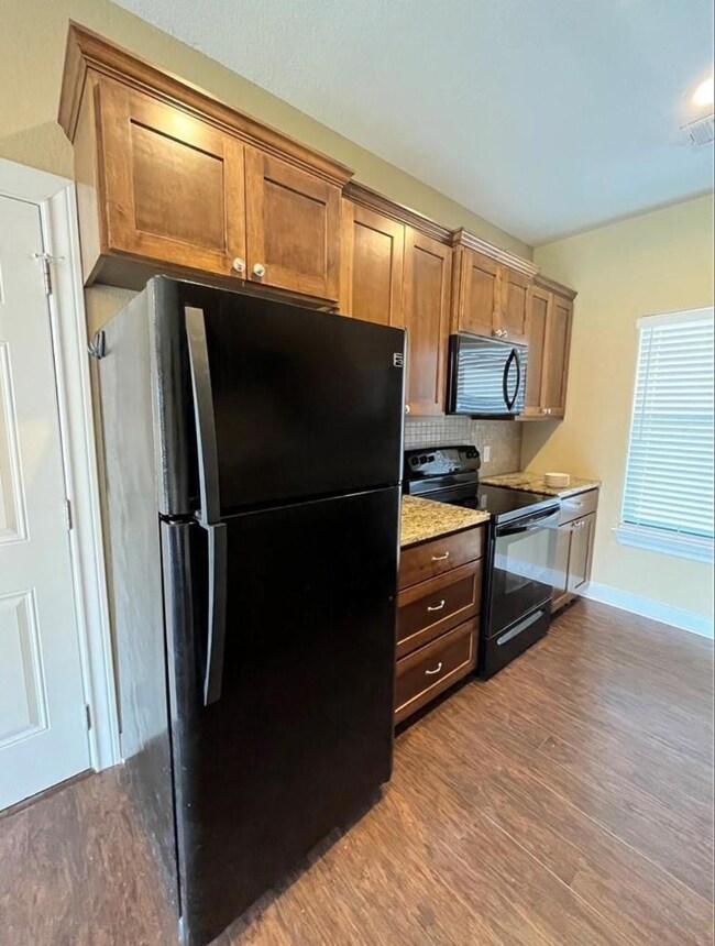 Kitchen with black appliances, light wood finishe