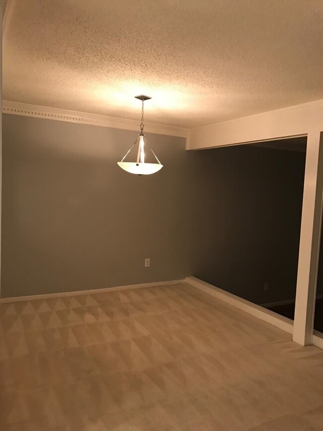 Empty room with light carpet, a textured ceiling, 