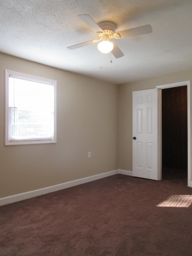 Spare room featuring dark colored carpet, a textur