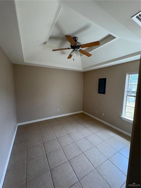 Unfurnished room featuring a raised ceiling, light tile patterned floors, ceiling fan, and baseboards