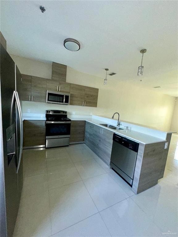 Kitchen with modern cabinets, stainless steel appliances, light tile patterned floors, and a peninsula