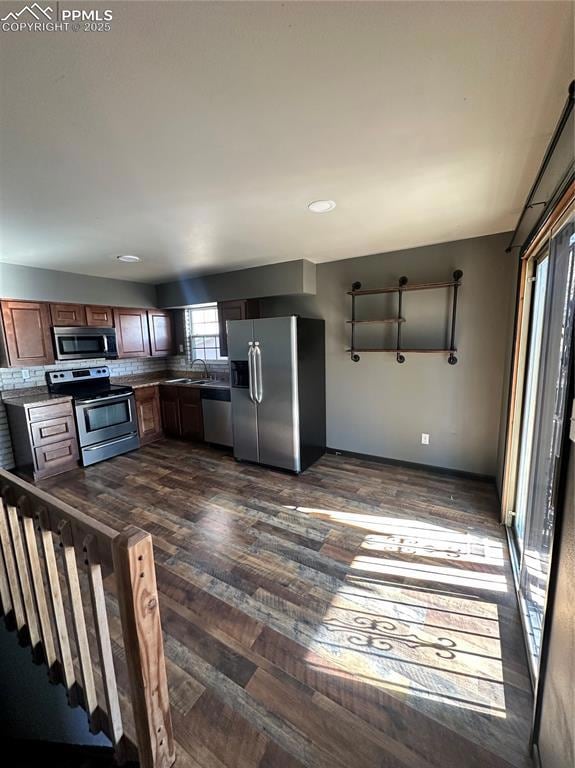 Kitchen featuring stainless steel fridge with ice dispenser, range, dark wood-type flooring, dishwashing machine, and recessed lighting
