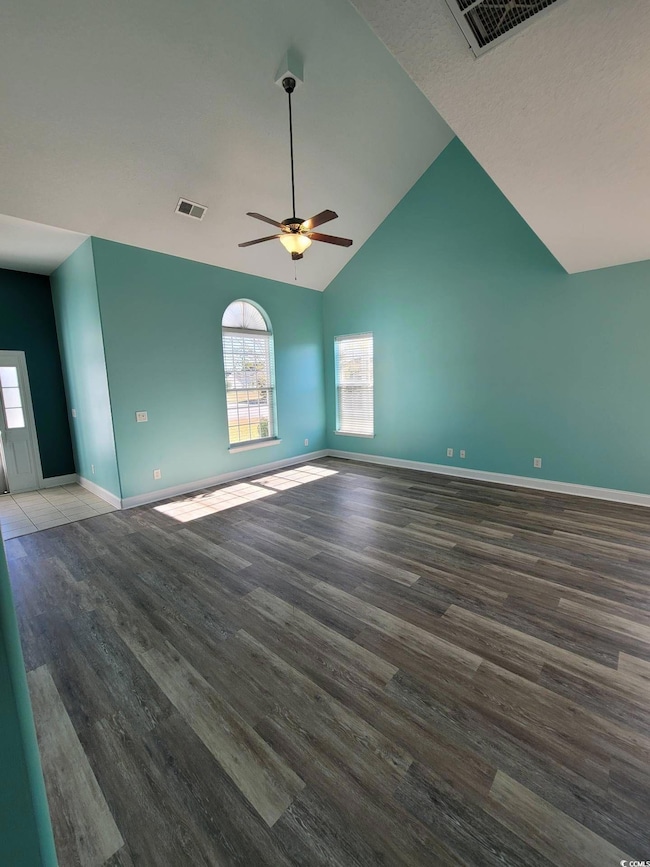 Spare room with wood finished floors, ceiling fan, and vaulted ceiling