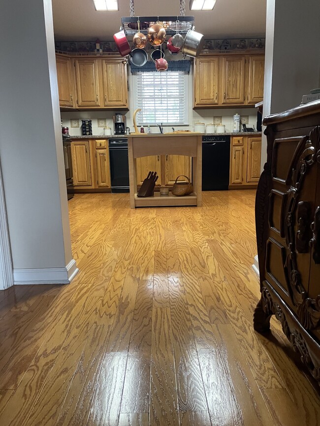 Look at these Beautiful Hardwood Floors leading to this open Kitchen that features plenty of cabinets and a large countertop.