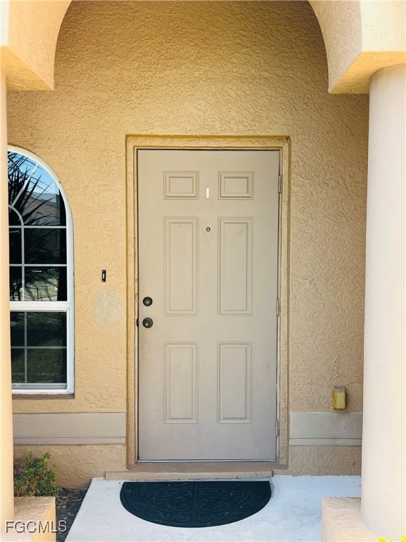 Doorway to property featuring stucco siding