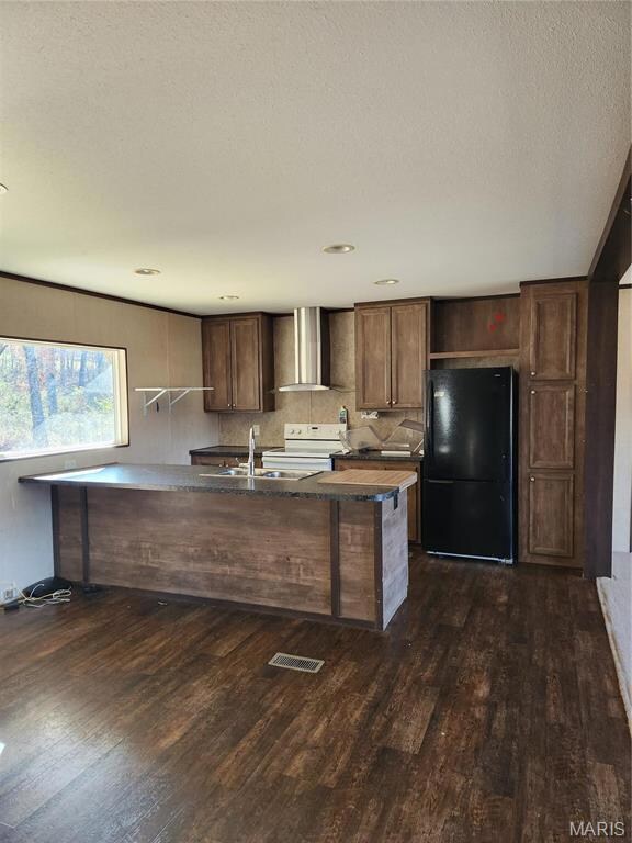 Kitchen featuring range hood, dark hardwood / wood-style floors, fridge, and range