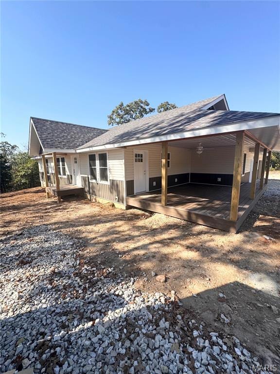 Back of property featuring a shingled roof, a porch, and an attached carport