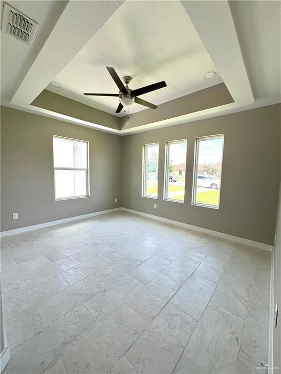 Empty room with a tray ceiling and ceiling fan