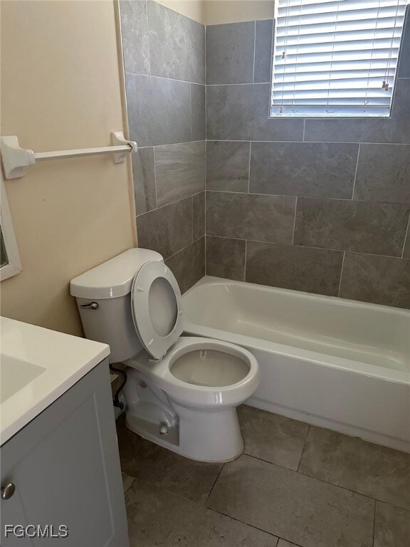 Bathroom featuring vanity, tub / shower combination, and tile patterned flooring