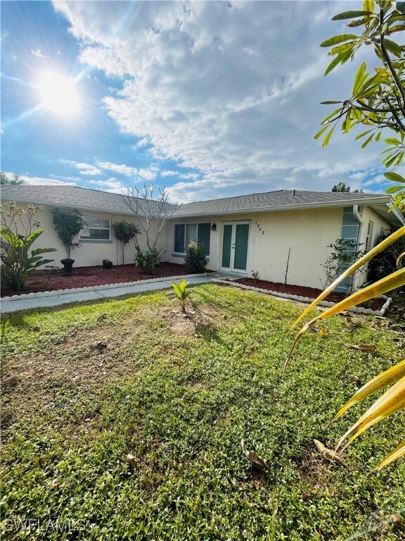 Rear view of property featuring a yard and french doors