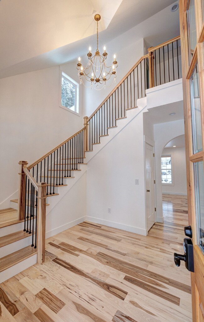 Staircase with a high ceiling, hardwood / wood-style floors, and a chandelier