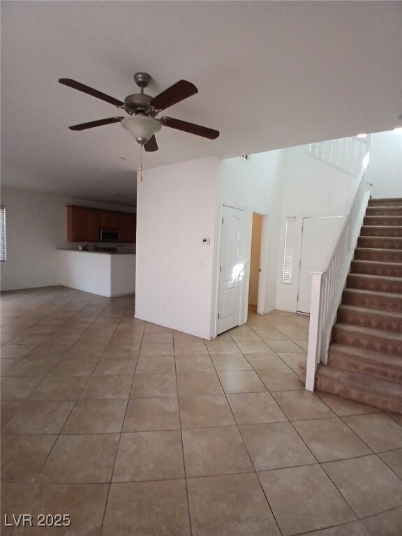 Unfurnished living room with stairs, ceiling fan,
