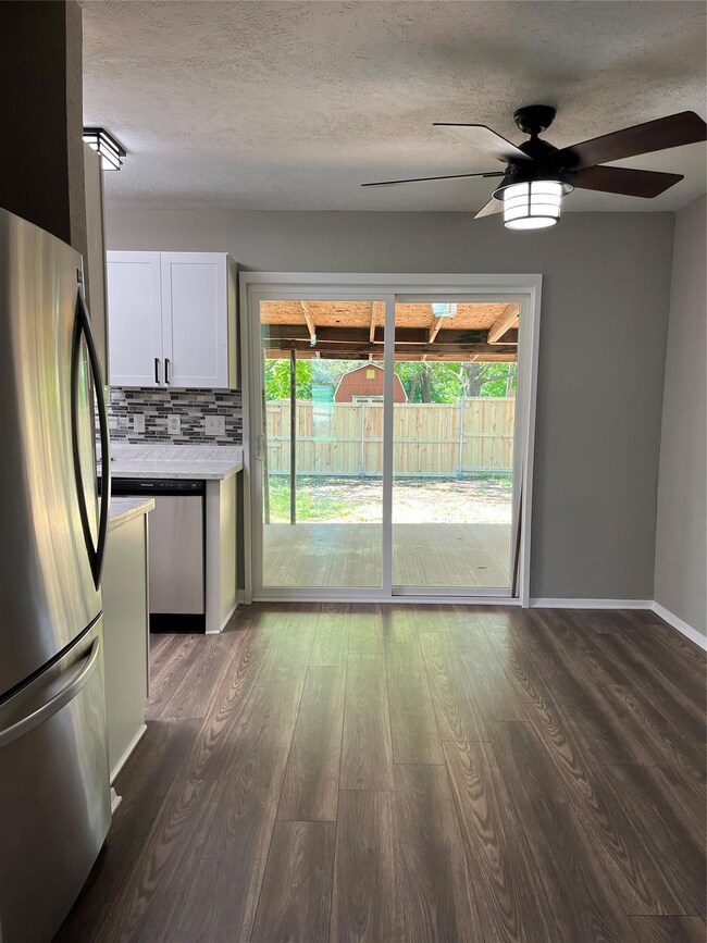 Kitchen with backsplash, dark hardwood / wood-style flooring, ceiling fan, and fridge