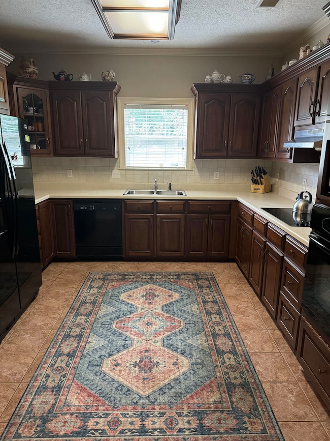 Kitchen with black appliances, light tile patterne