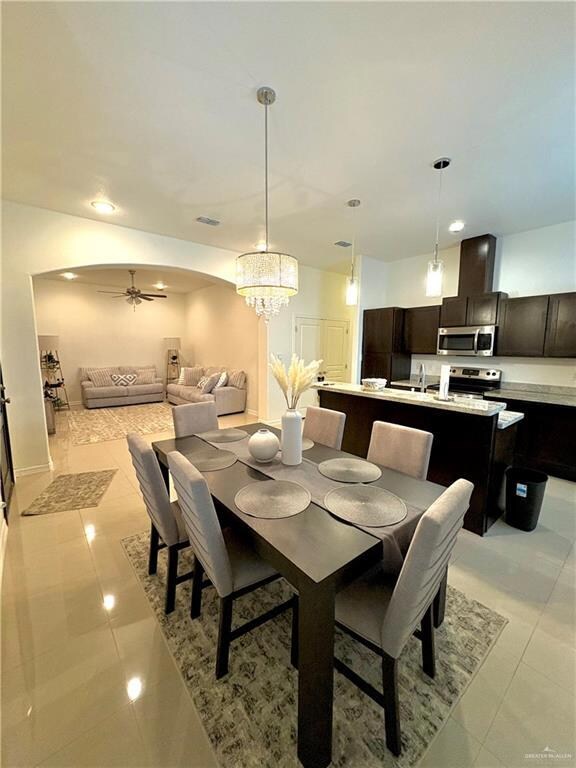 Tiled dining room with ceiling fan and sink