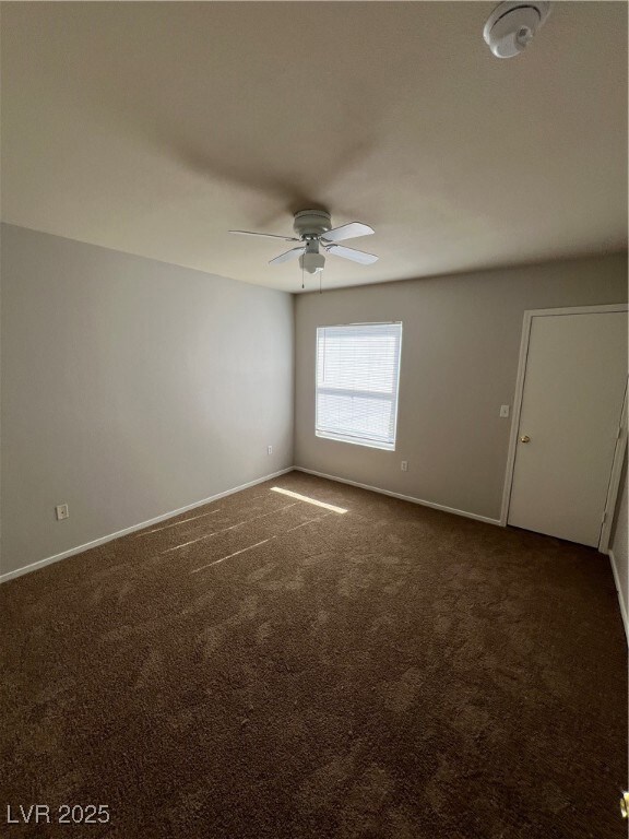 Unfurnished room with dark carpet, a smoke detector, and a ceiling fan
