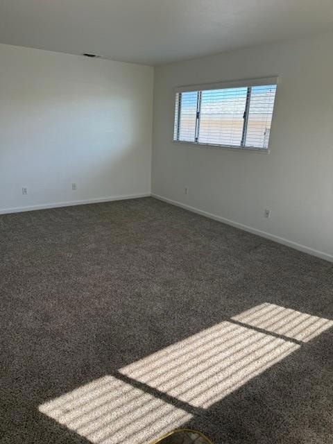 carpeted spare room featuring baseboards