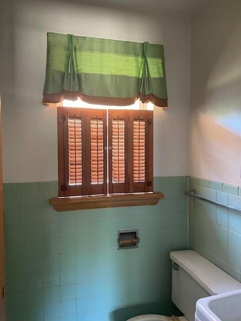 Bathroom featuring tile walls and toilet
