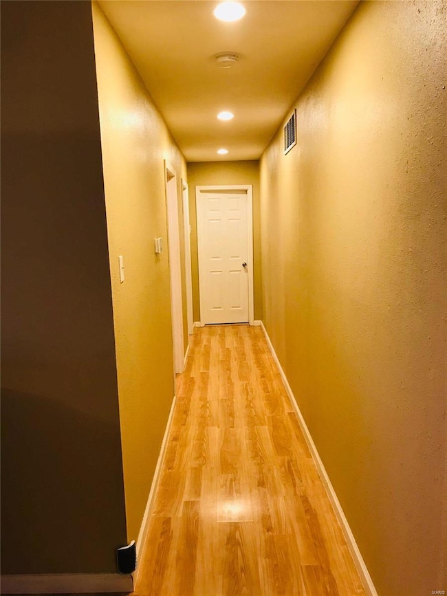 Hallway with recessed can lighting leading to the 