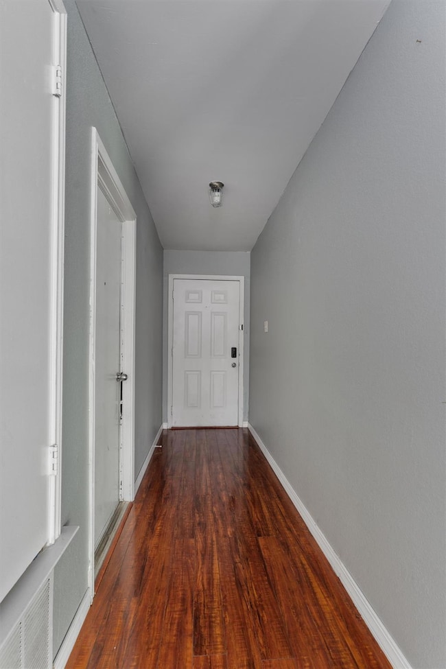 Doorway featuring baseboards and wood finished fl