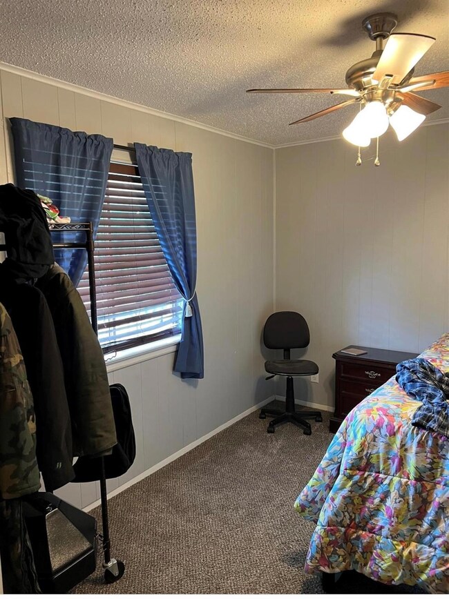 Bedroom with carpet flooring, ceiling fan, and a t