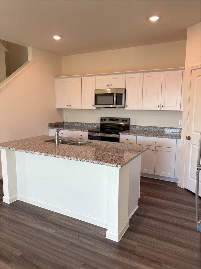 Kitchen with white cabinetry, dark stone countertops, stainless steel range with electric cooktop, recessed lighting, and dark wood-style floors
