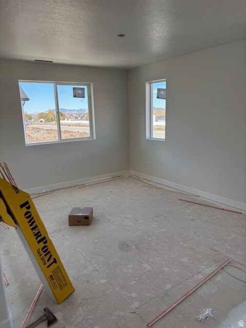 Unfurnished room featuring a textured ceiling and baseboards