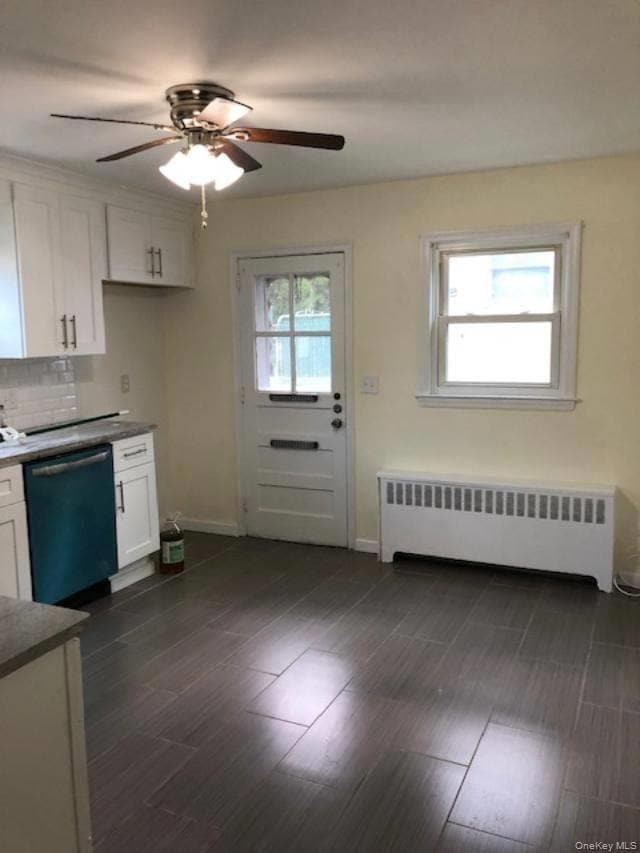 Kitchen with white cabinets, radiator heating unit, dishwasher, dark countertops, and dark wood-style flooring