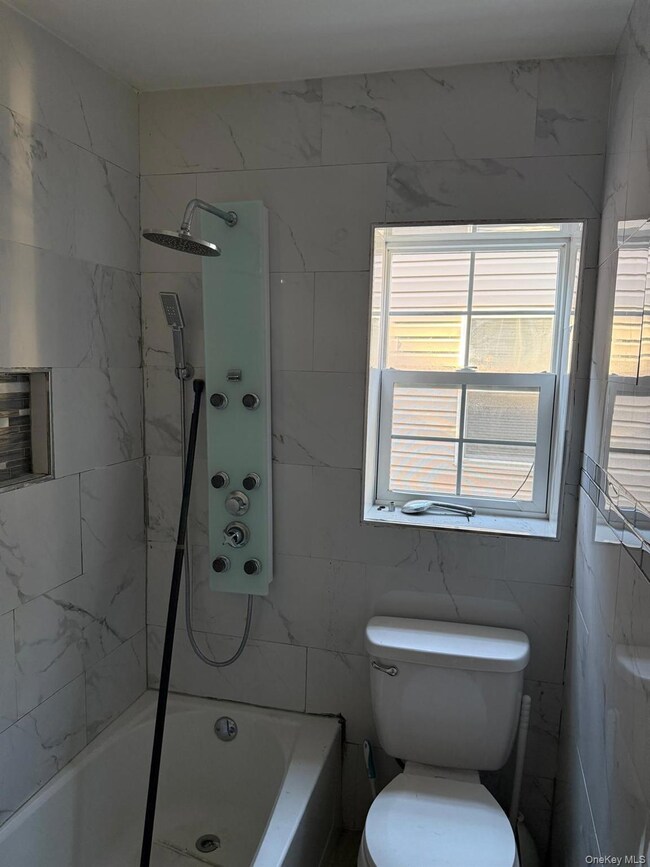 Bathroom featuring shower / bathtub combination and tile walls