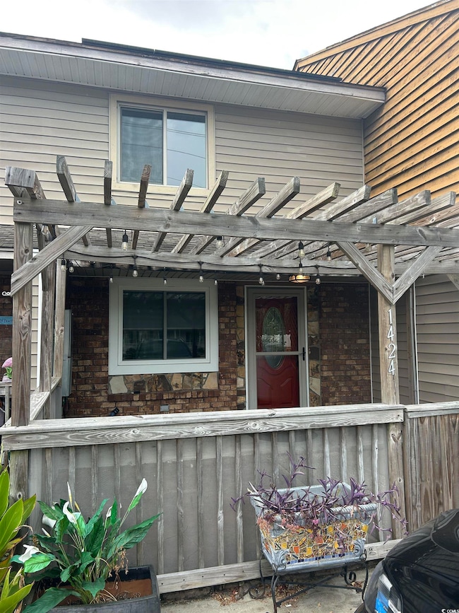 Property entrance featuring a pergola and brick siding