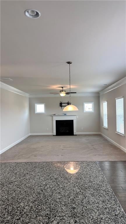 Unfurnished living room featuring ornamental molding, a fireplace, baseboards, plenty of natural light, and wood finished floors