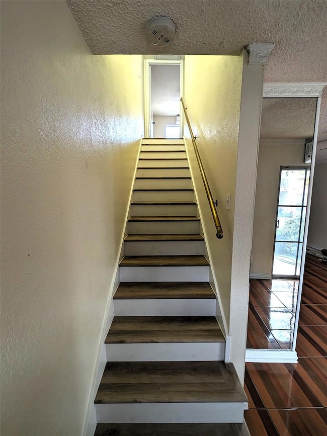 Staircase featuring a textured wall, baseboards, w